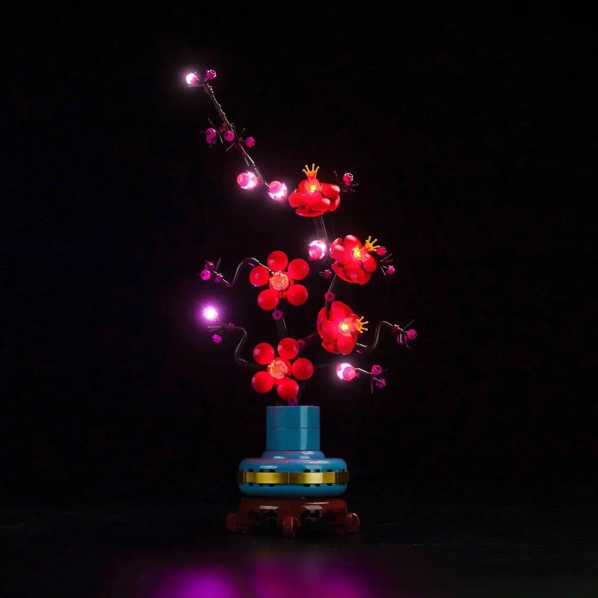 Beleuchteter Lego Pflaumenblütenzweig in einer blauen Vase vor schwarzem Hintergrund