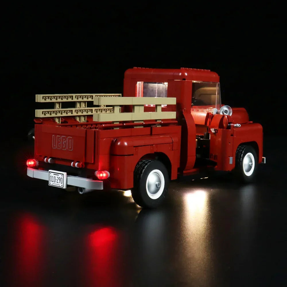 Roter Lego Pickup Truck mit beleuchteten Scheinwerfern und Rücklichtern auf schwarzem Hintergrund