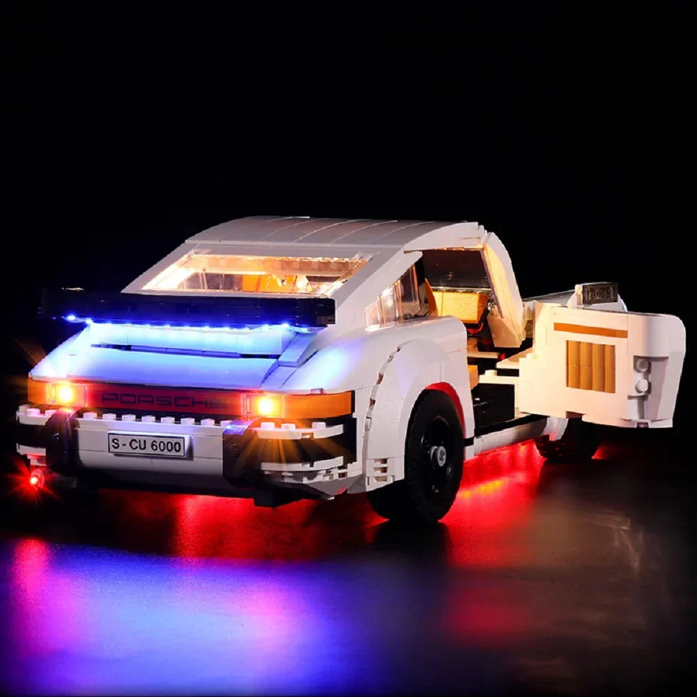 Weißes Porsche Modellauto aus Klemmbausteinen mit eingeschalteter LED Beleuchtung vor schwarzem Hintergrund