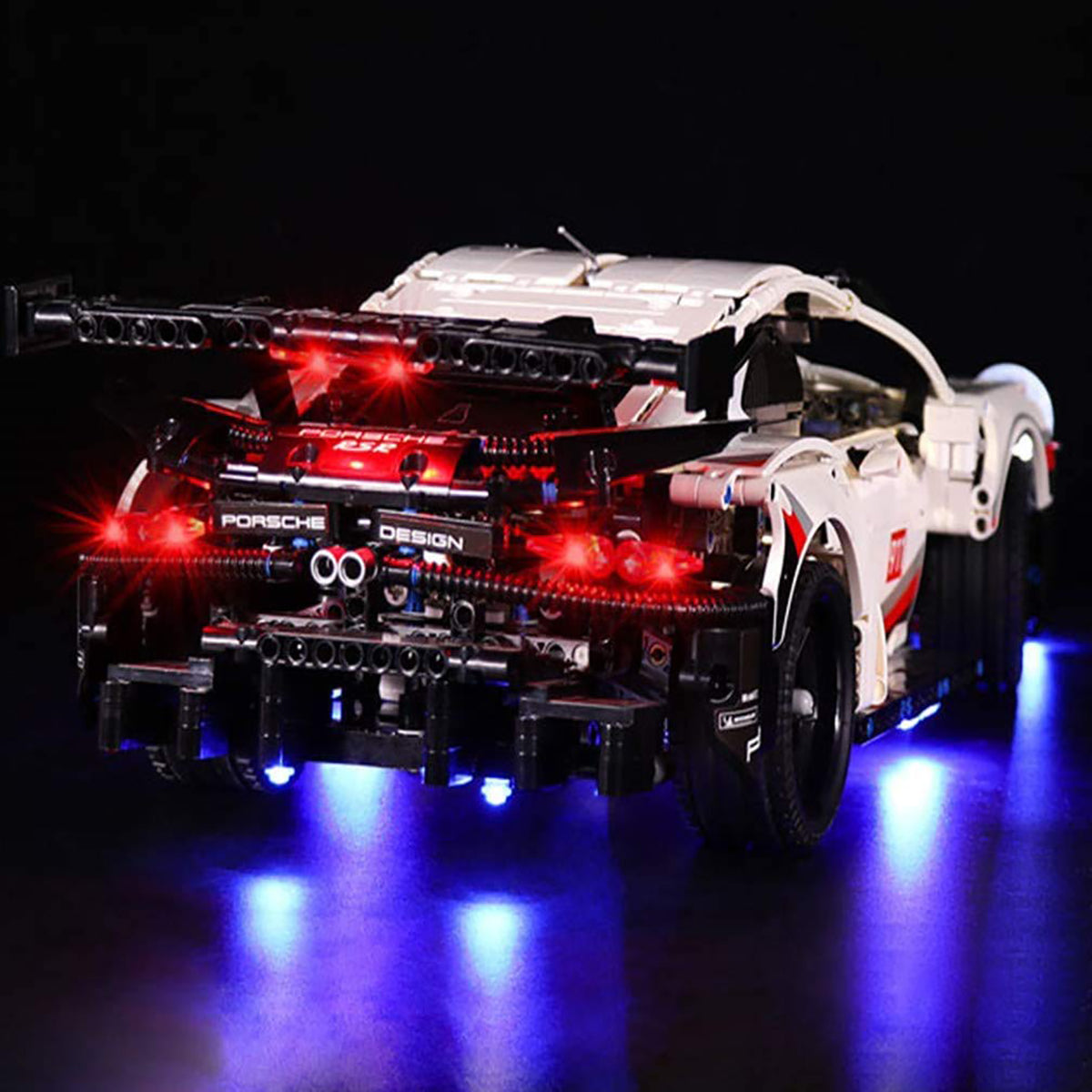 Modellauto Porsche RSR mit roter Heckbeleuchtung und blauer Unterbodenbeleuchtung auf schwarzem Hintergrund