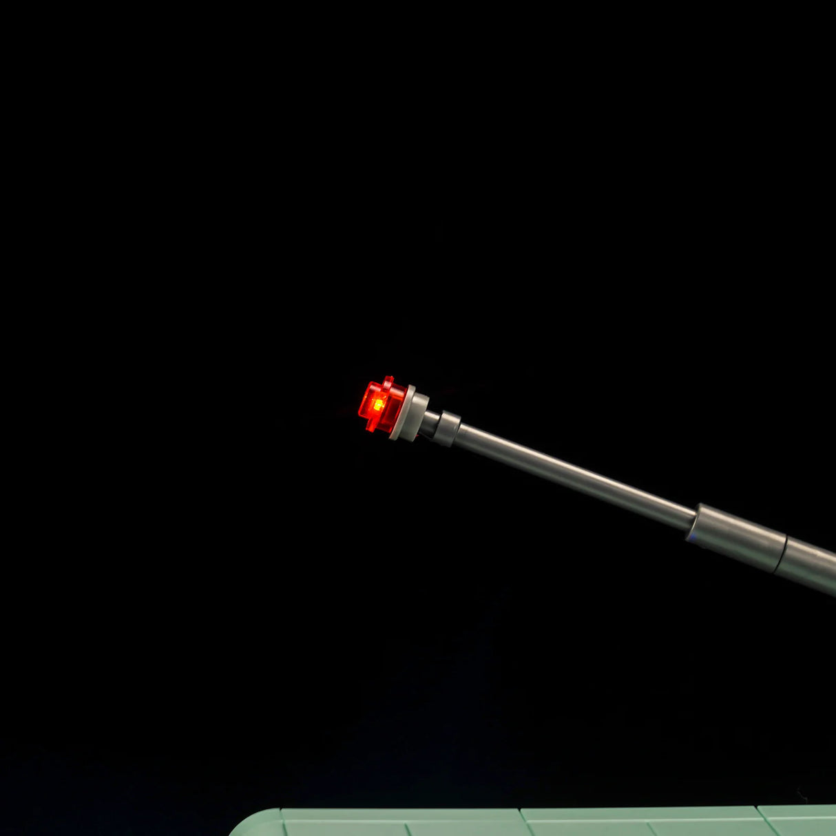 Leuchtende rote LED an einer grauen Antenne vor schwarzem Hintergrund