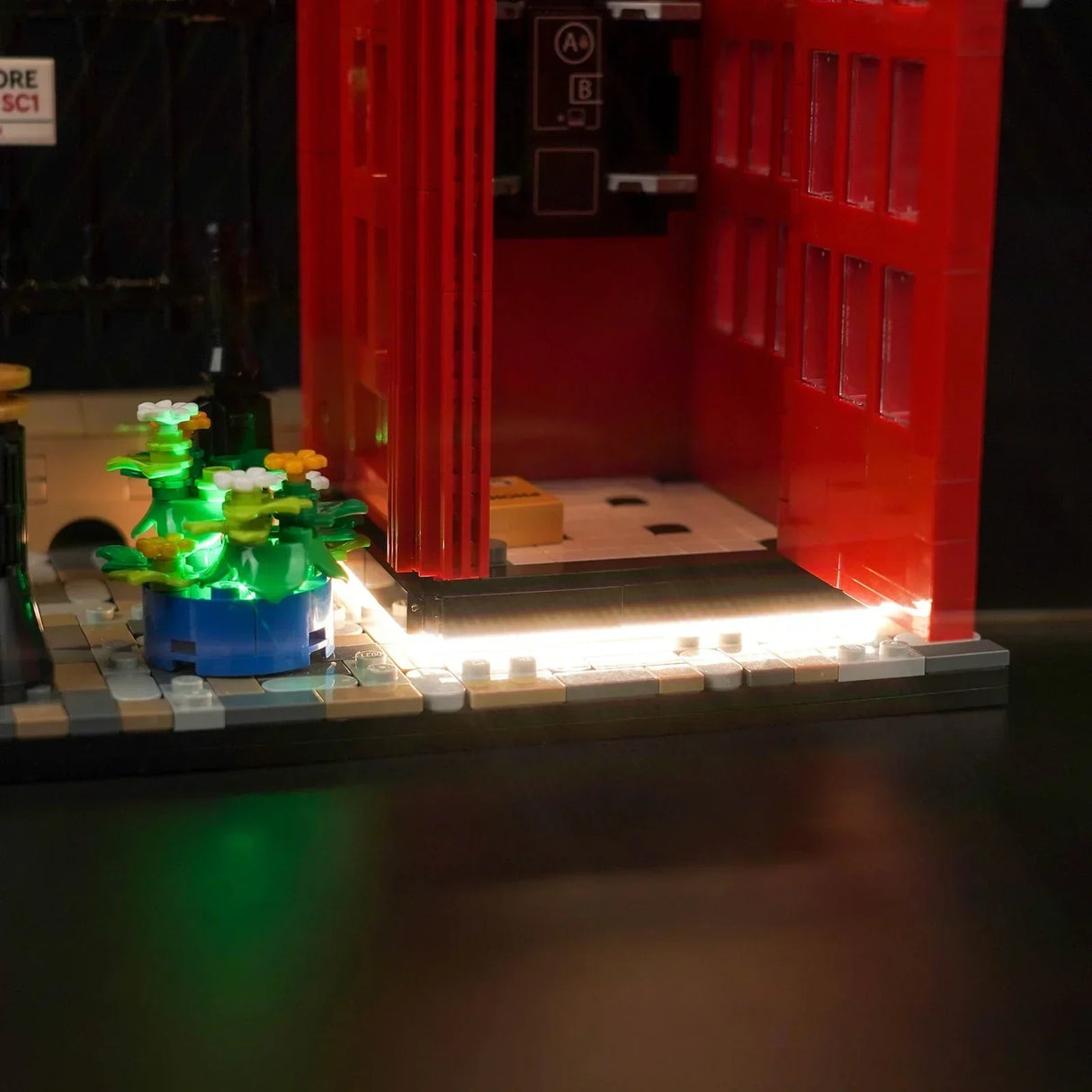 Beleuchtetes Lego Modell einer roten Telefonzelle mit Blumenkübel