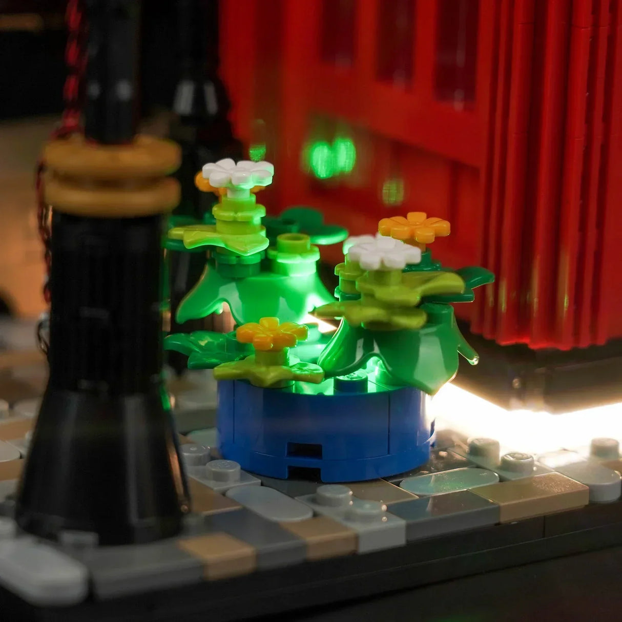 Beleuchtete Lego Blumen in einem blauen Topf neben einer Laterne