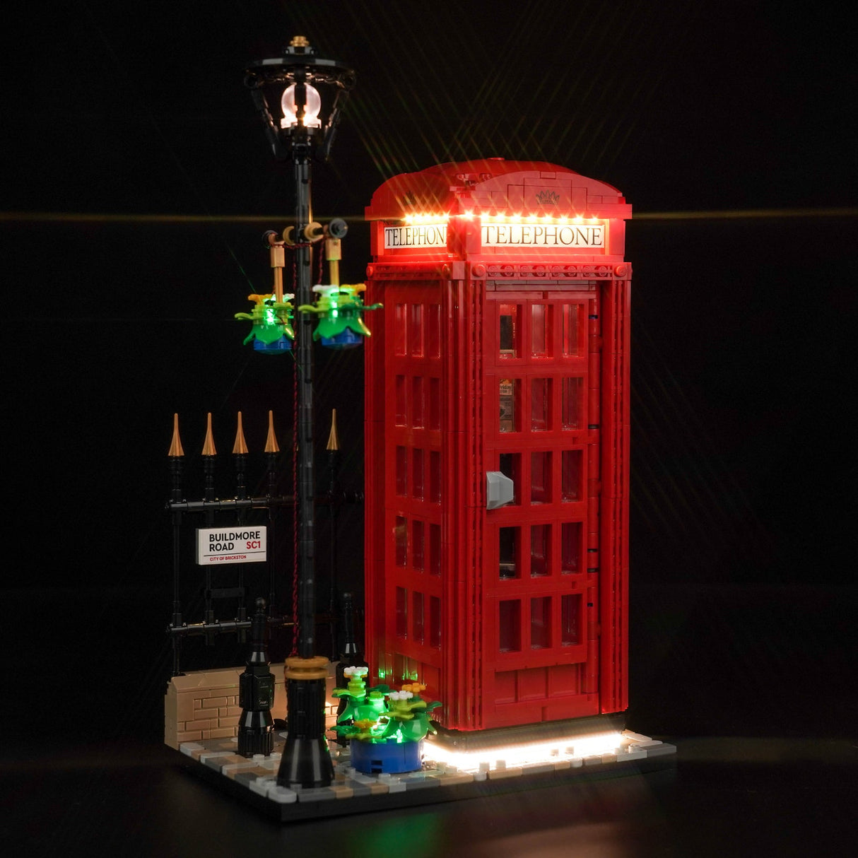 Beleuchtetes Lego Modell einer roten britischen Telefonzelle mit Straßenlaterne vor schwarzem Hintergrund