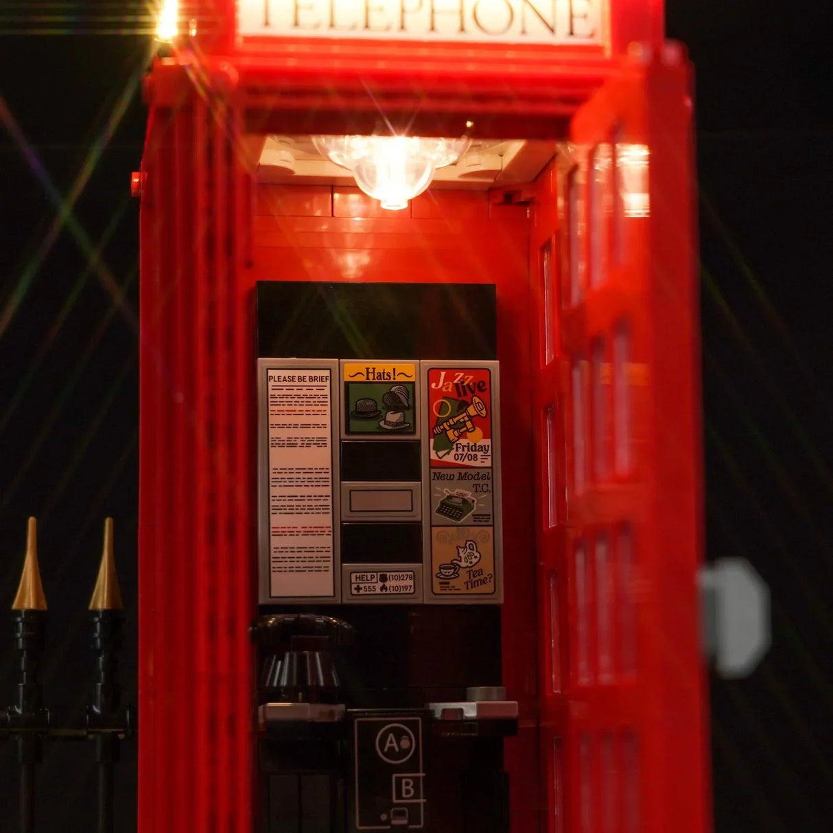 Innenansicht einer roten Lego Telefonzelle mit beleuchtetem Innenraum und detaillierten Aufklebern an der Wand