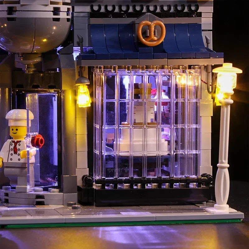 Beleuchtetes Lego Gebaeude mit einer Kochfigur vor dem Eingang und einer Brezel am Gebaeude