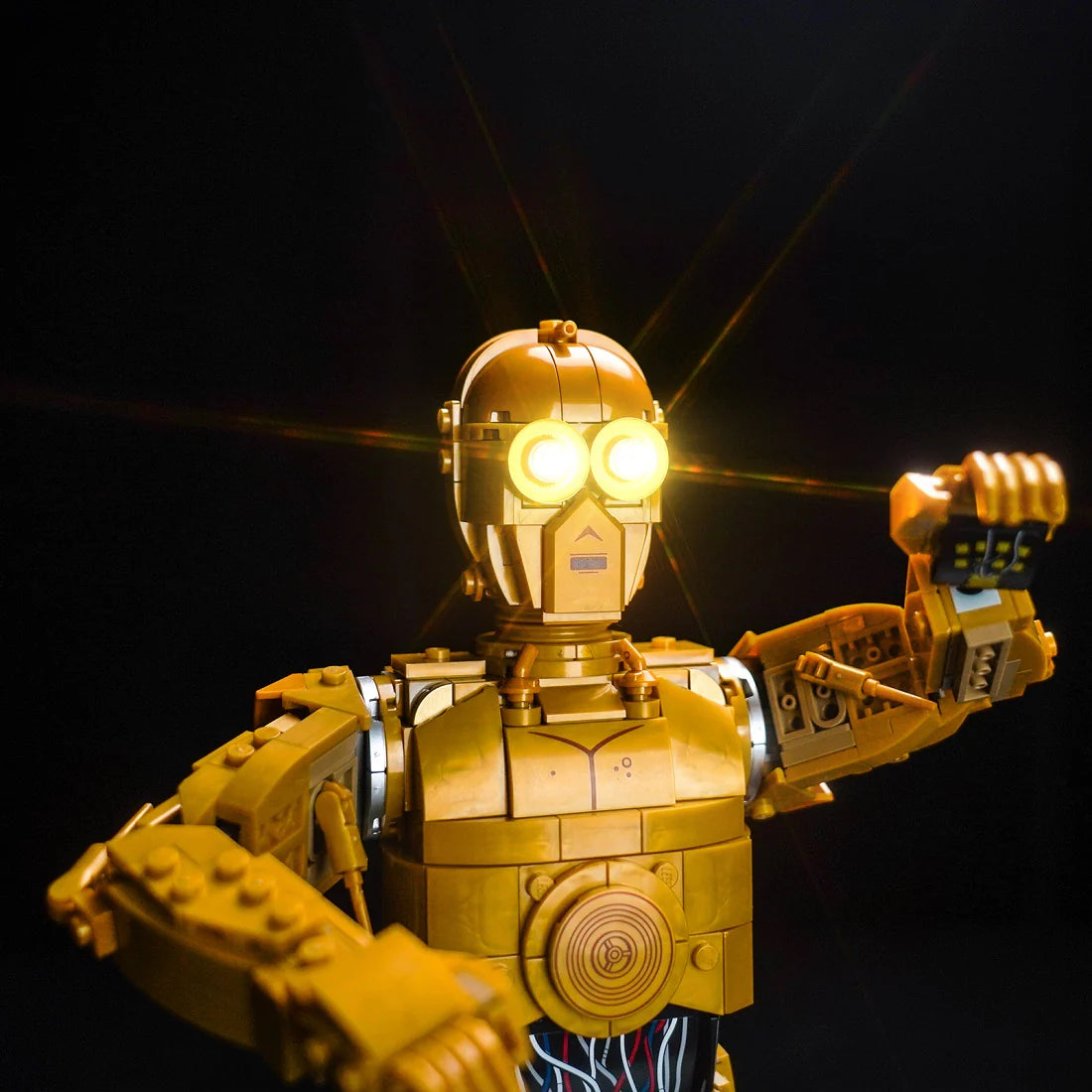 Goldene C-3PO Lego Figur mit leuchtenden Augen vor schwarzem Hintergrund