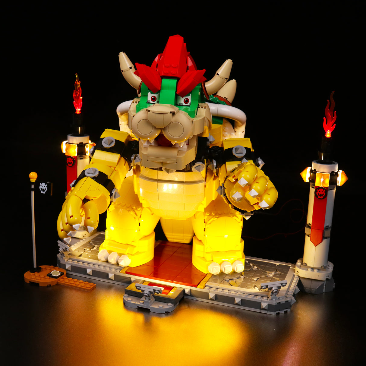 Beleuchtete Lego Bowser Figur auf einer Plattform mit zwei Fackeln