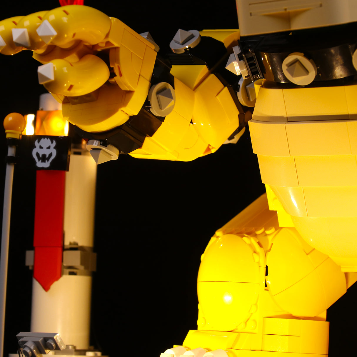 Nahaufnahme eines gelben Lego Bowser Modells mit Stachelarmband vor schwarzem Hintergrund