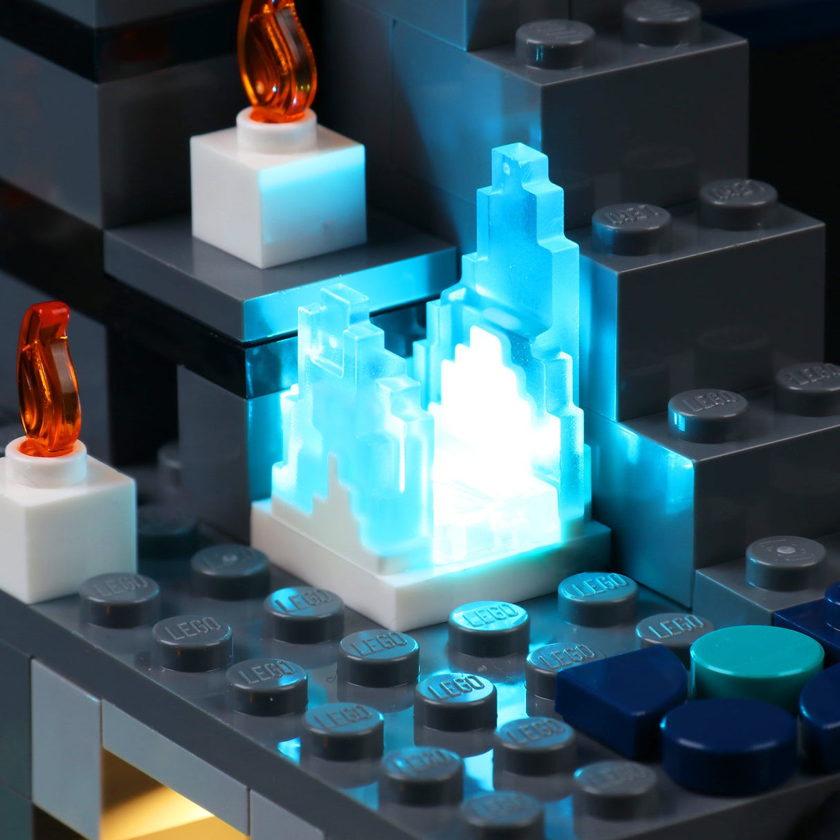 Beleuchtetes blaues Kristallobjekt auf einer grauen Lego Basis mit orangefarbenen Flammen