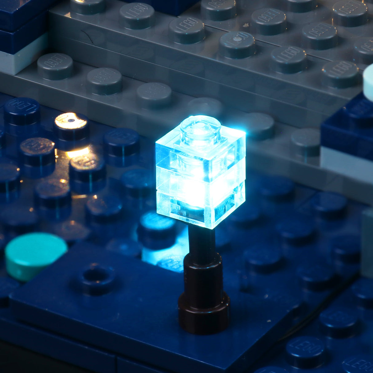 Leuchtender blauer Baustein auf einer blauen Lego Grundplatte