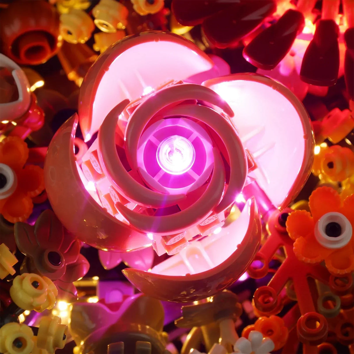 Draufsicht auf die zentral leuchtende, rosa-pinke Rose des LEGO 10314 Gestecks mit stimmungsvollem LED-Lichteffekt.