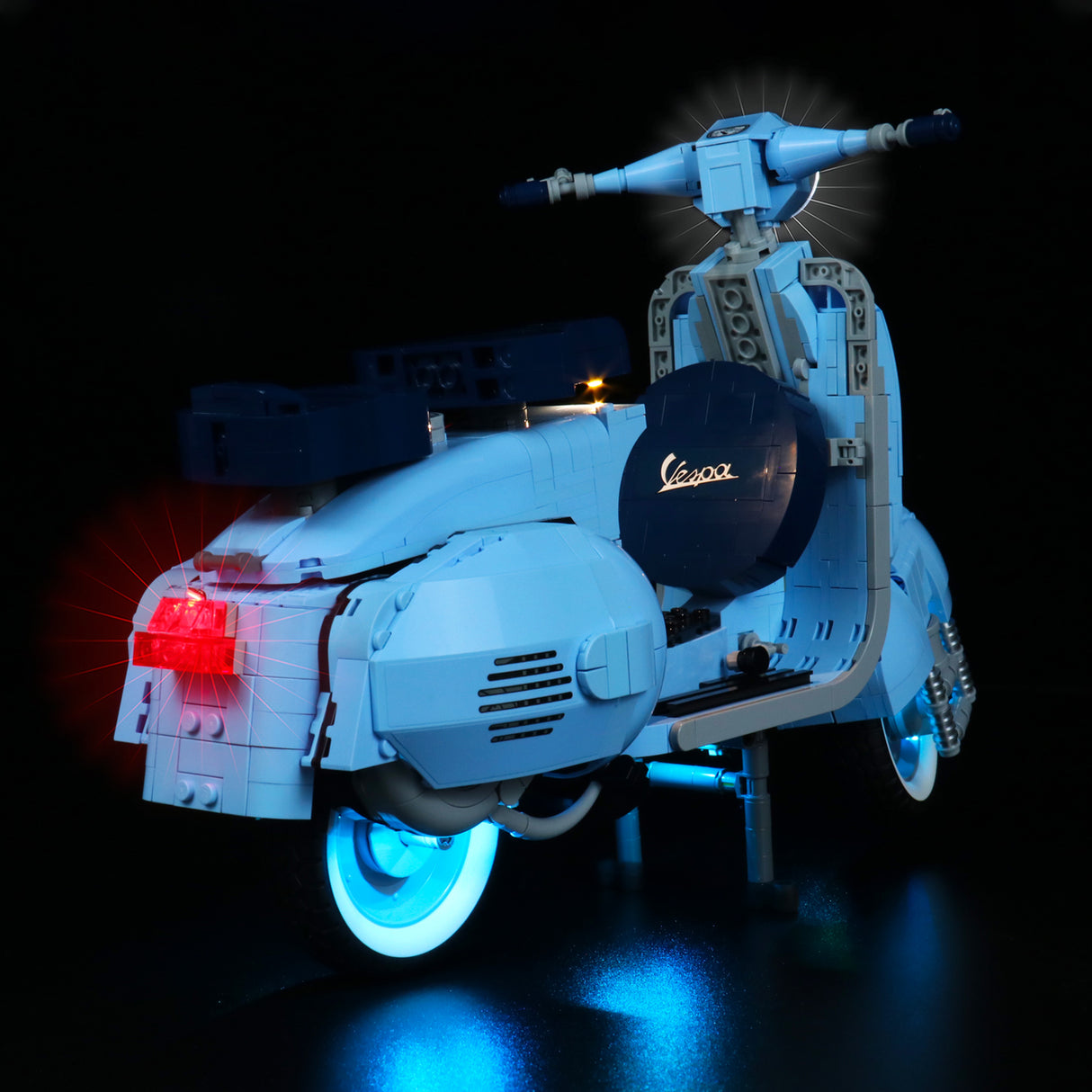 Hellblaues Vespa Modell aus Klemmbausteinen mit leuchtenden Scheinwerfern und Rücklicht vor schwarzem Hintergrund