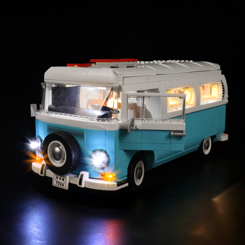 Beleuchtetes Modell eines blau-weißen Campingbusses aus Klemmbausteinen vor schwarzem Hintergrund