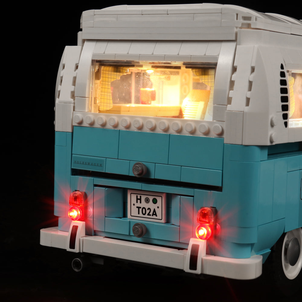 Heckansicht eines hellblauen und weissen Lego Campingbusses mit leuchtenden Rücklichtern und Innenbeleuchtung