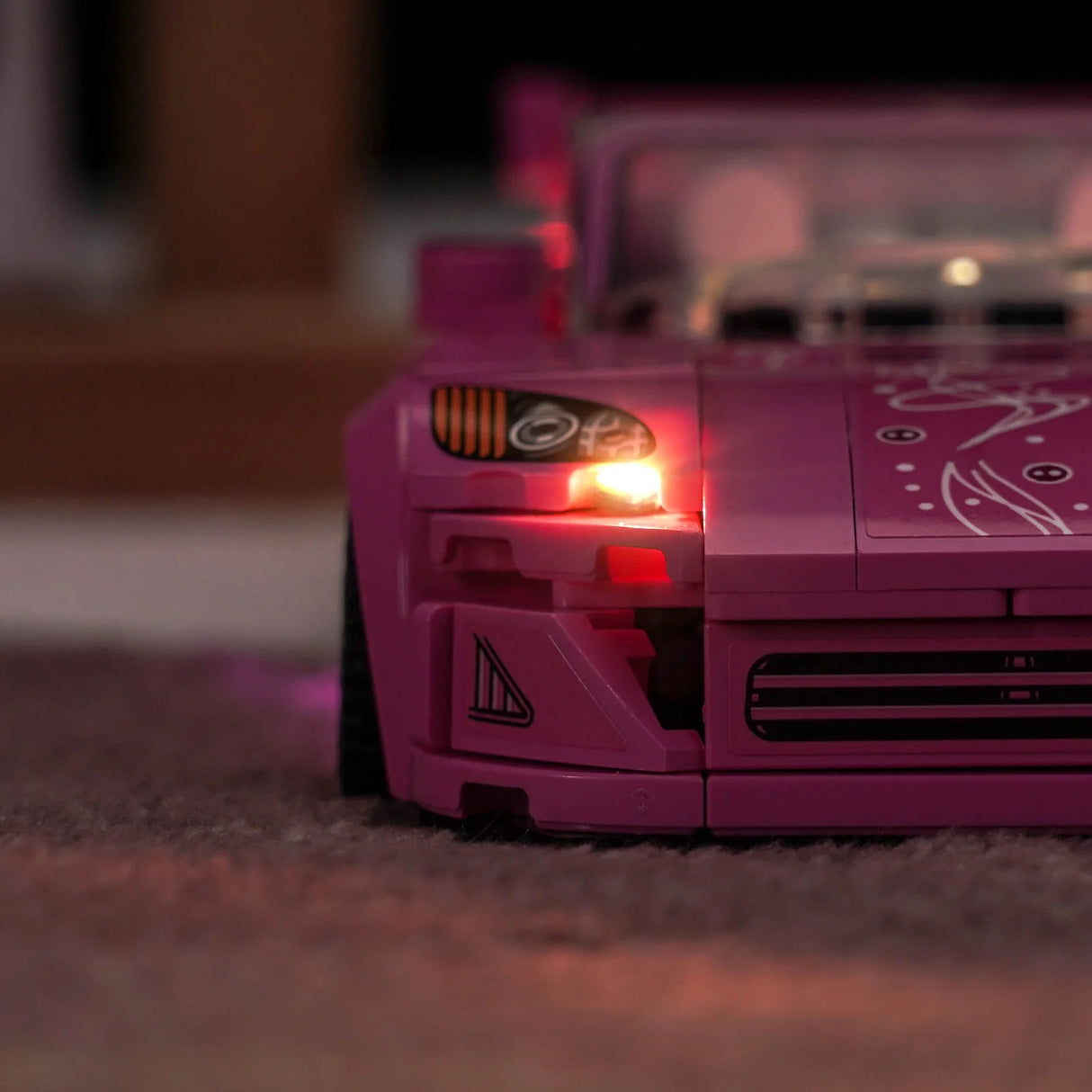 Nahaufnahme eines rosa Spielzeugautos mit leuchtenden Scheinwerfern auf einem Teppich