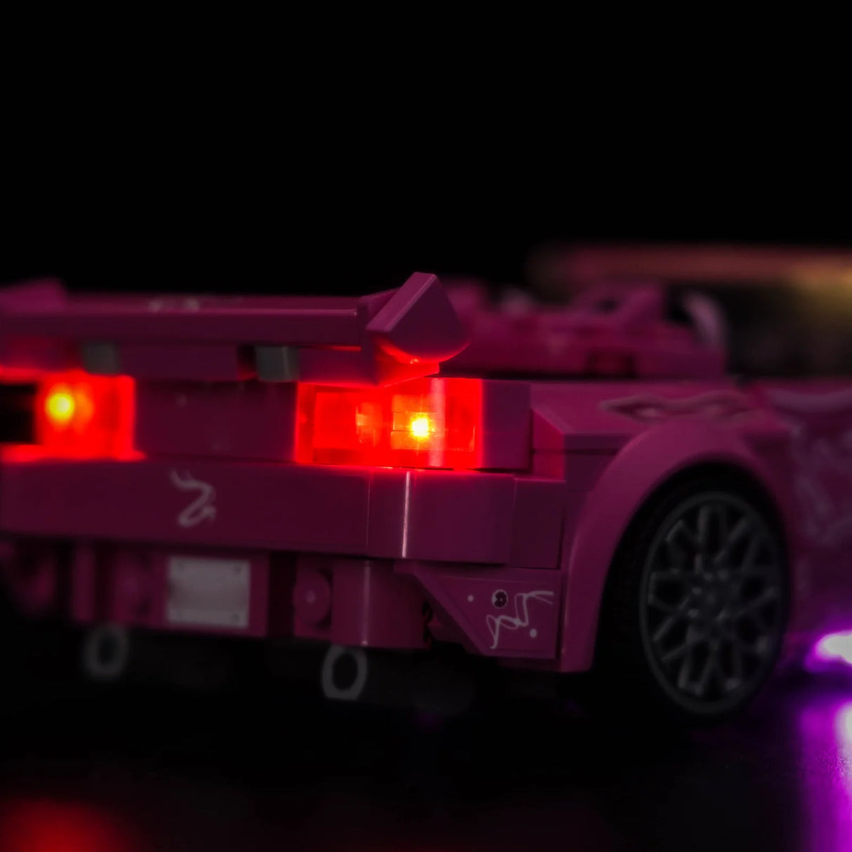 Rückansicht eines pinkfarbenen Spielzeugautos mit leuchtenden roten Rücklichtern und einem Spoiler