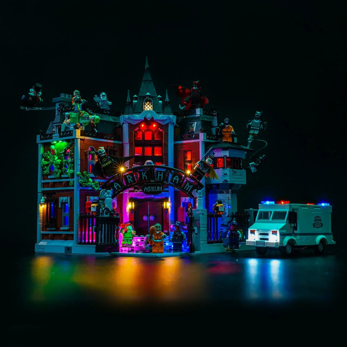 Beleuchtetes LEGO Arkham Asylum mit Minifiguren und einem geparkten Krankenwagen