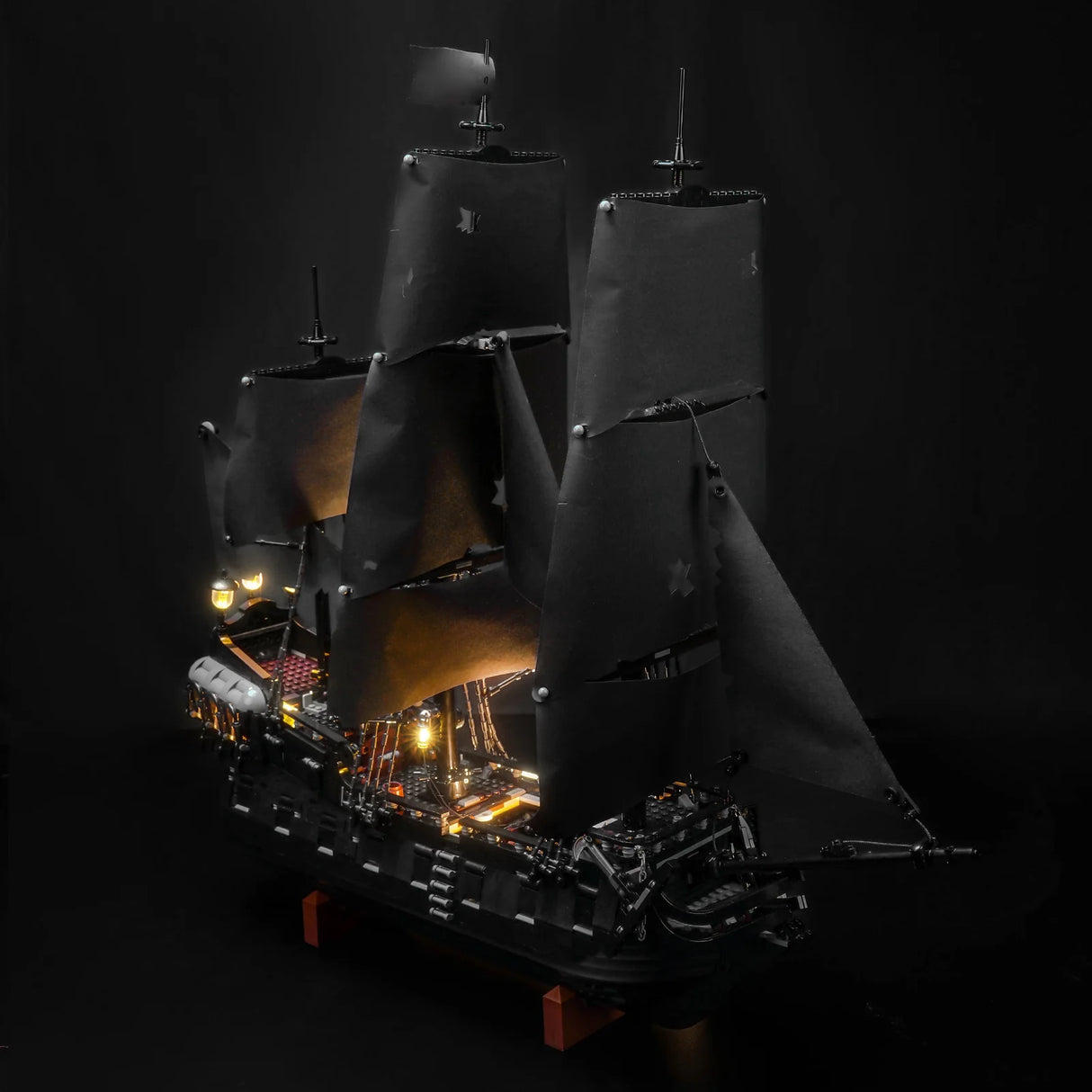Beleuchtetes Modell eines schwarzen Piratenschiffs mit Segeln auf schwarzem Hintergrund