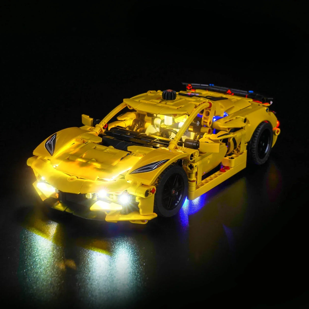 Gelbes Lego-Auto mit leuchtenden Scheinwerfern und blauer Unterbodenbeleuchtung auf schwarzem Hintergrund