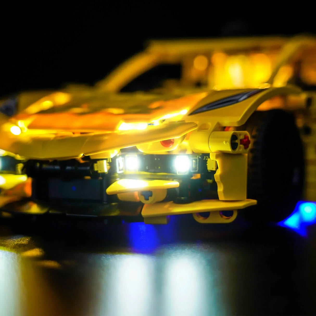 Gelbes Spielzeugauto mit leuchtenden Scheinwerfern und blauen Unterbodenlichtern