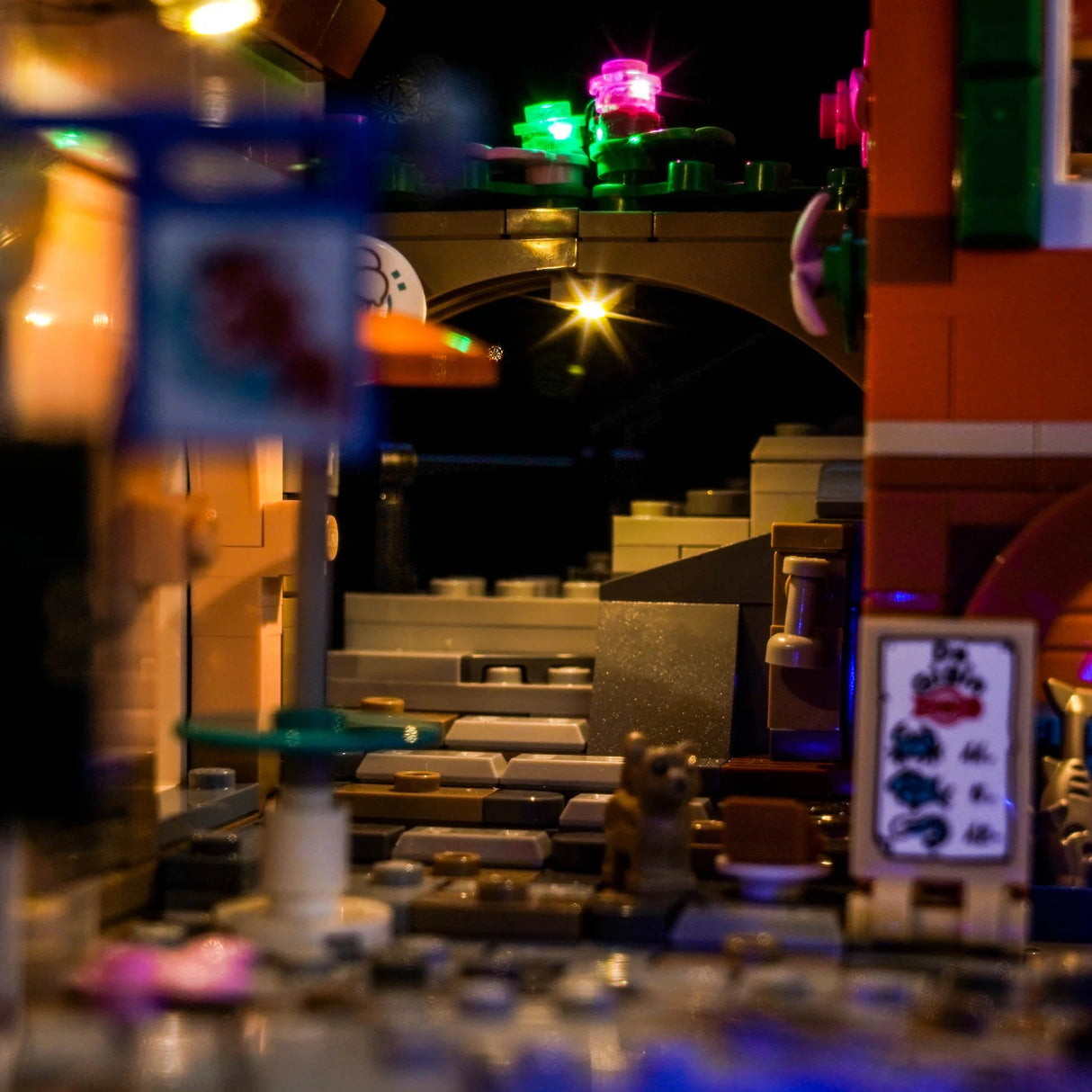 Nahaufnahme eines beleuchteten LEGO-Sets bei Nacht mit einem Bogen und bunten Lichtern