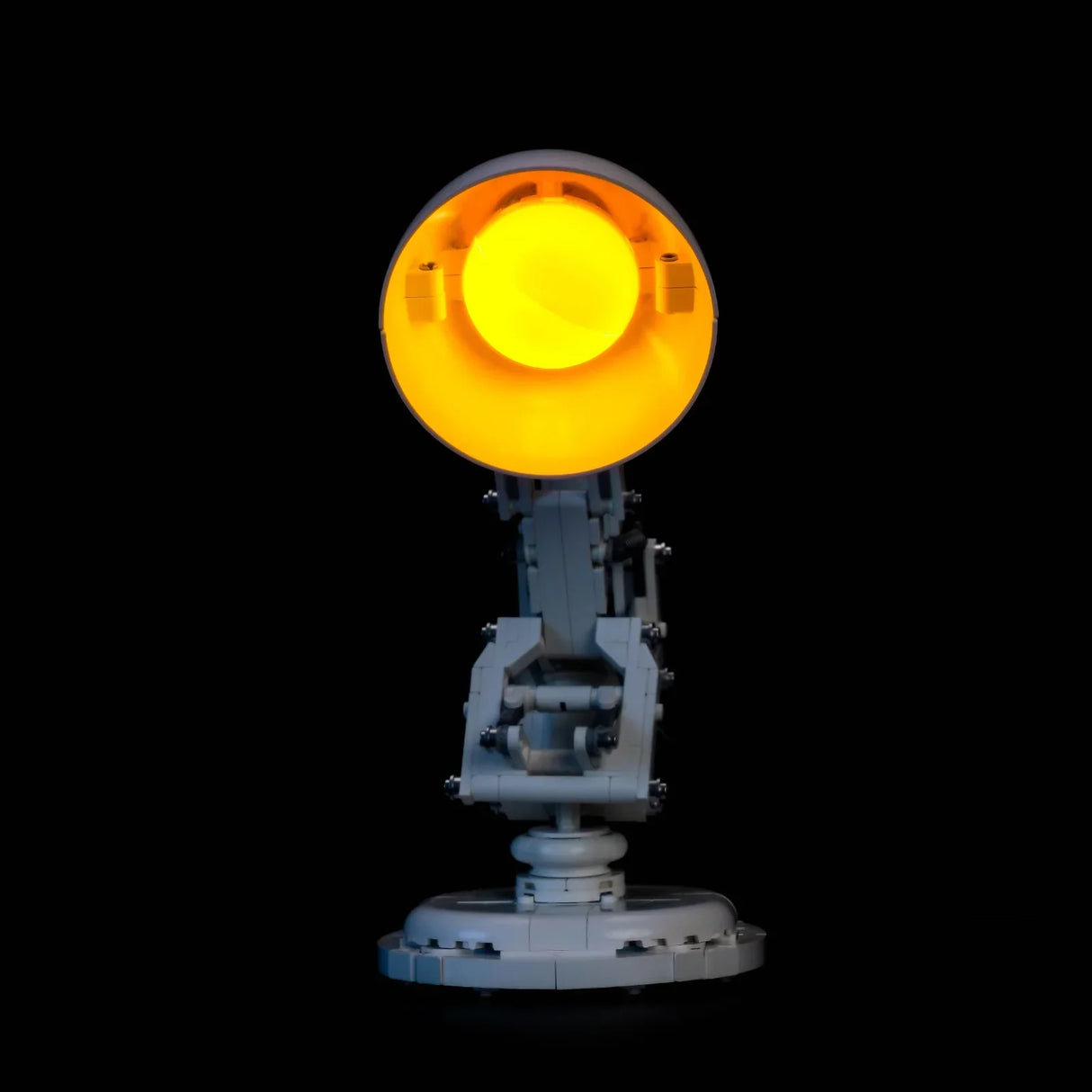 Eine graue Schreibtischlampe mit leuchtend gelbem Licht auf schwarzem Hintergrund