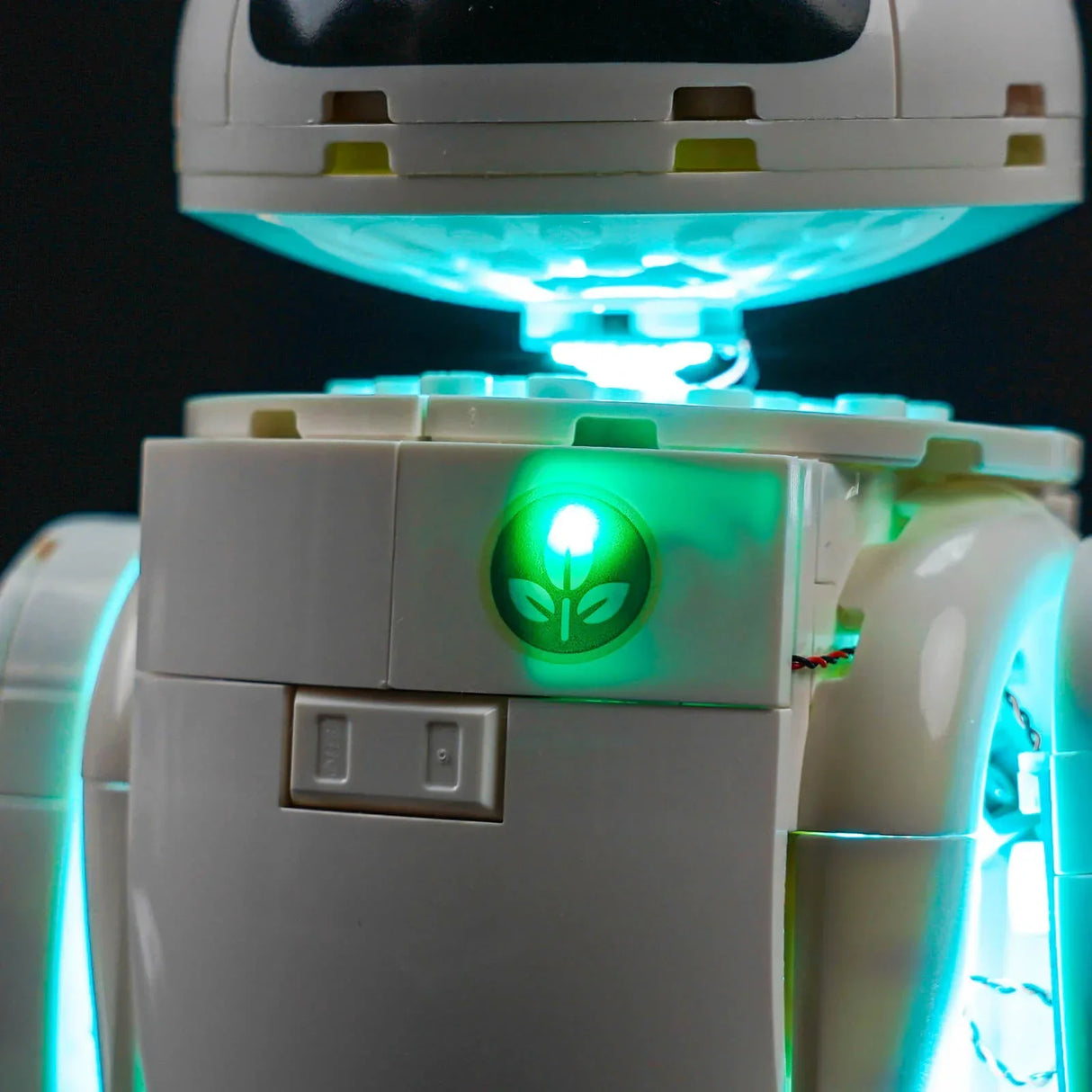 Nahaufnahme eines weißen Roboters mit leuchtend blauem Licht und einem grünen Blattlogo auf der Brust