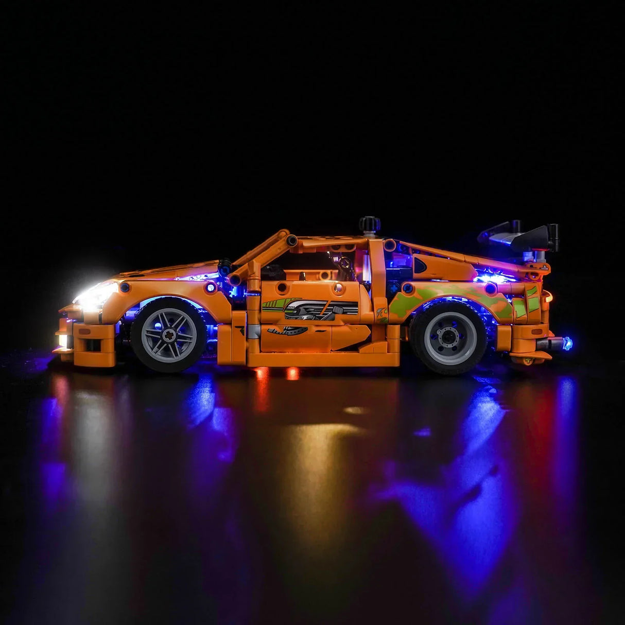 Orangefarbenes Spielzeugauto mit leuchtenden blauen und weißen Lichtern auf schwarzem Hintergrund