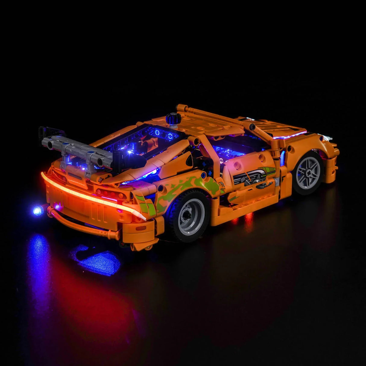 Orangefarbenes Spielzeugauto mit blauen und roten Lichtern auf schwarzem Hintergrund