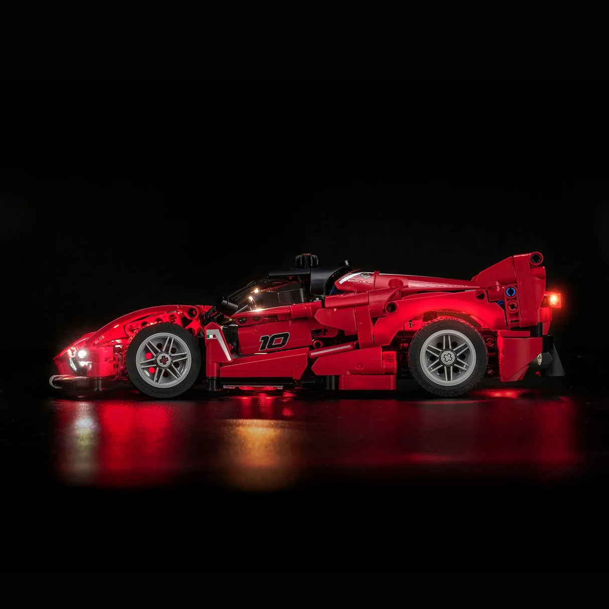 Rotes Lego-Rennauto mit leuchtenden Scheinwerfern und Rücklichtern auf schwarzem Hintergrund
