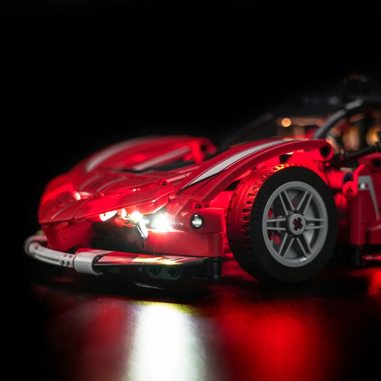 Rotes Spielzeugauto mit leuchtenden Scheinwerfern und roten Lichtern auf schwarzem Hintergrund