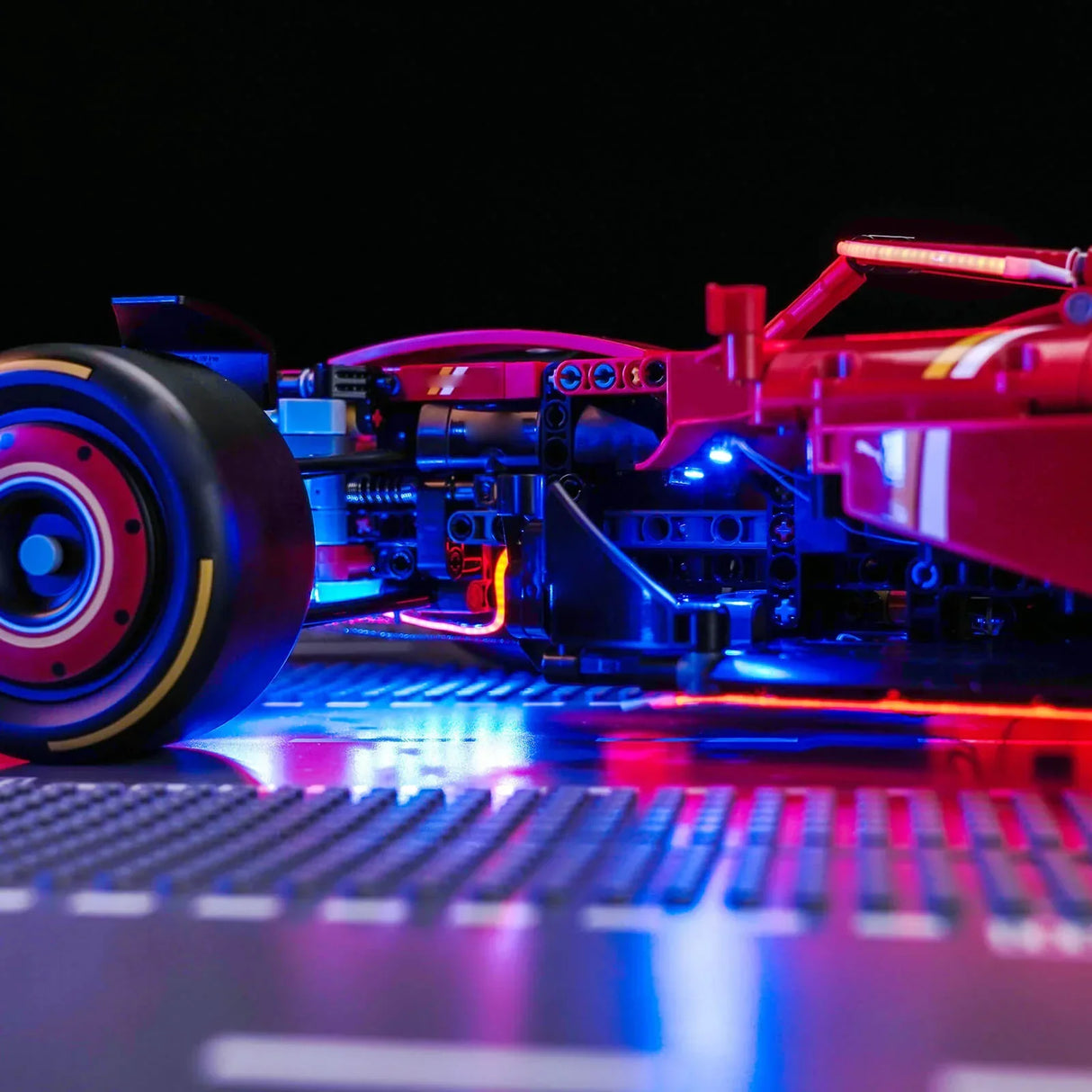 Rotes Formel-1-Modellauto mit blauen und roten Lichtern auf einer dunklen Oberfläche