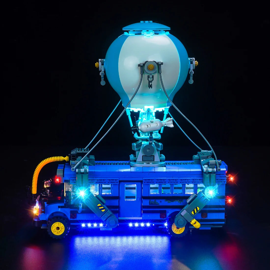 Beleuchtetes Lego Modell eines blauen Busses mit Heißluftballon vor schwarzem Hintergrund