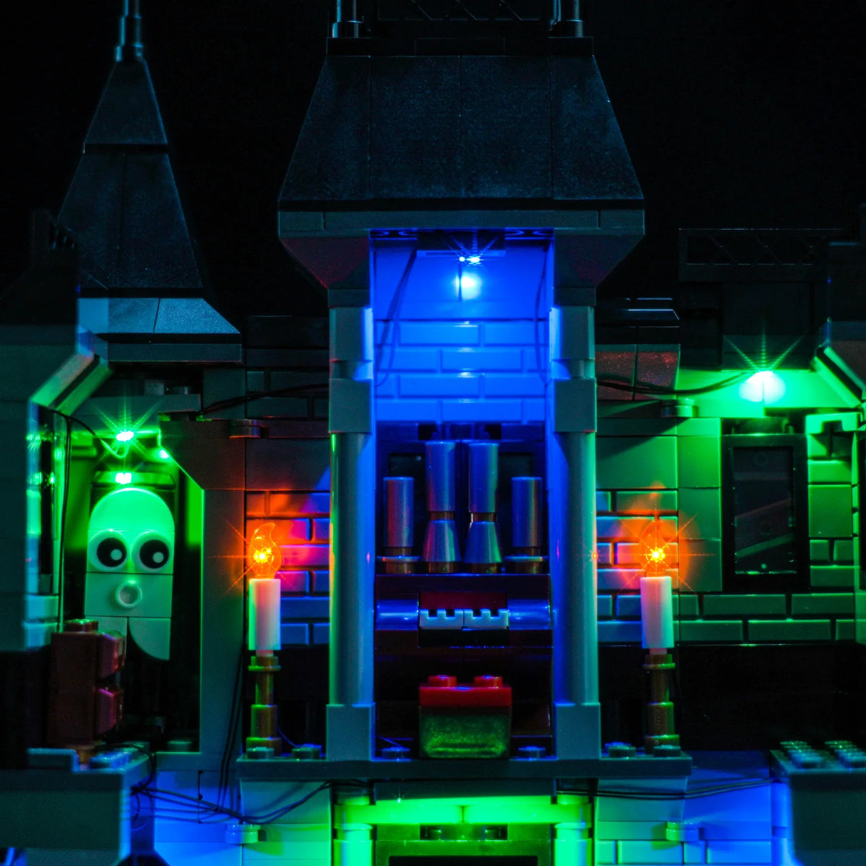 Nahaufnahme eines beleuchteten Lego-Geisterhauses mit blauen und grünen Lichtern und Kerzen