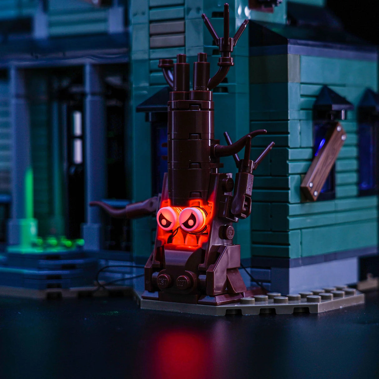 Ein LEGO Baum mit leuchtenden roten Augen vor einem grünen LEGO Haus