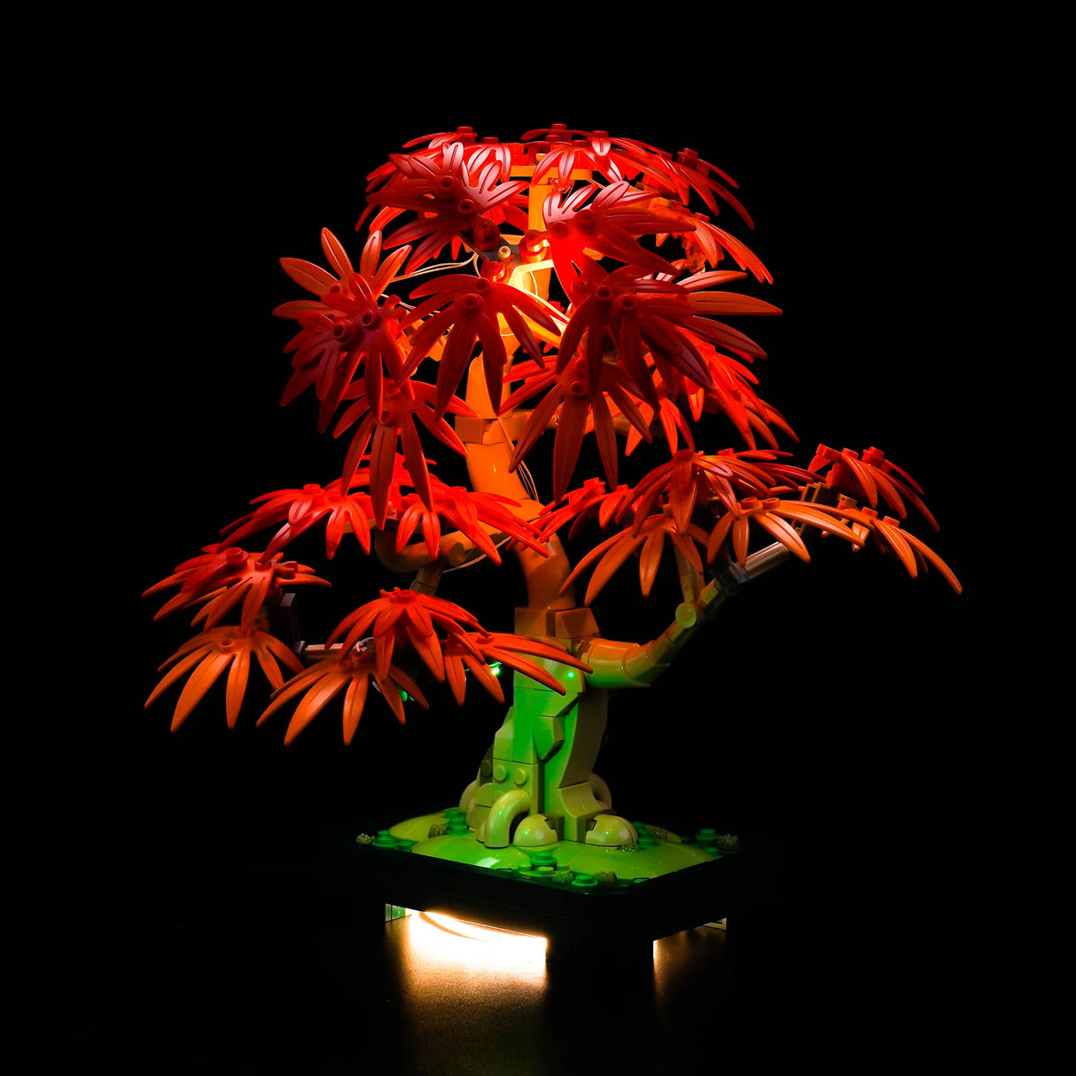 Beleuchteter LEGO Bonsai-Baum mit roten Blättern und grünem Stamm auf schwarzem Hintergrund
