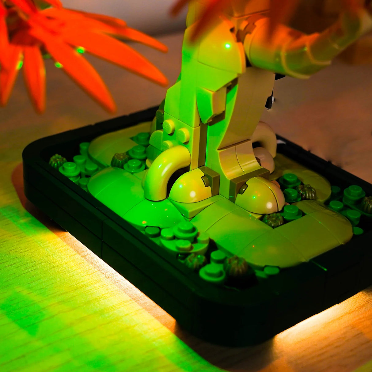 Nahaufnahme eines leuchtenden Lego-Bonsai-Baums in einem Topf mit orangefarbenen Blättern im Hintergrund