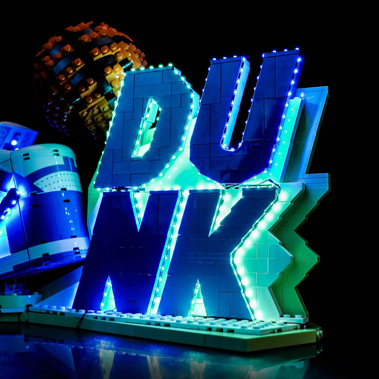 Lego-Schriftzug DUNK mit blauen und grünen Lichtern, daneben ein Lego-Basketball und ein Lego-Schuh