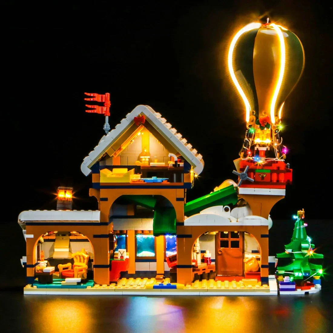 Beleuchtetes Lego Weihnachtsmodell mit Heißluftballon und Tannenbaum vor schwarzem Hintergrund