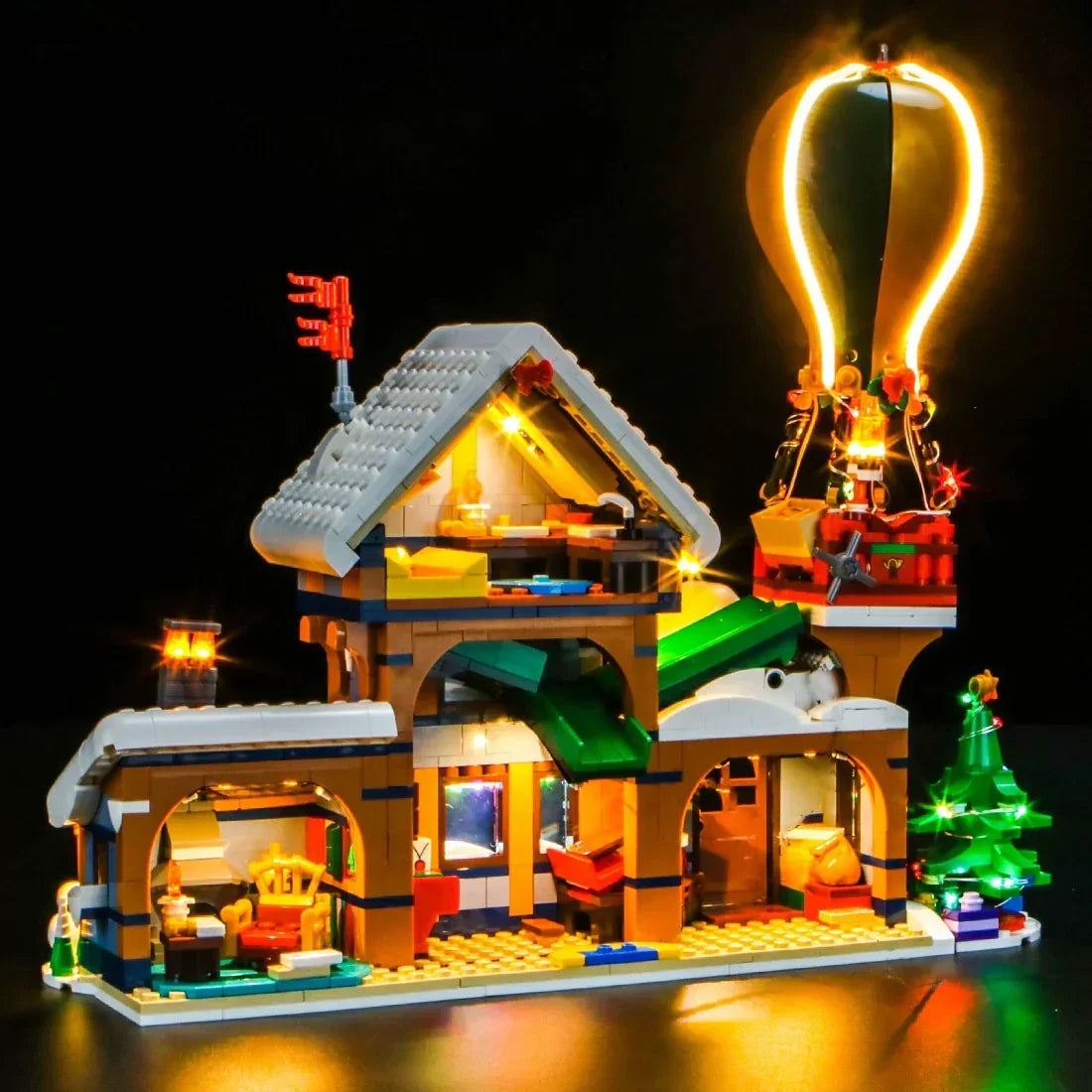 Beleuchtetes Lego Weihnachtsmodell mit Heißluftballon und geschmücktem Tannenbaum vor schwarzem Hintergrund