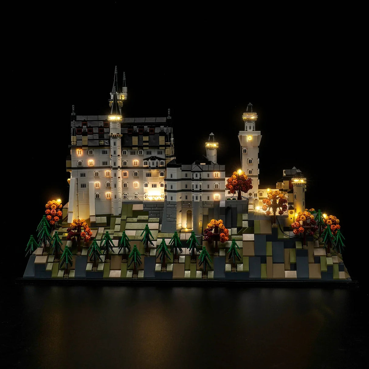 Beleuchtetes Schlossmodell mit Bäumen und Türmen bei Nacht