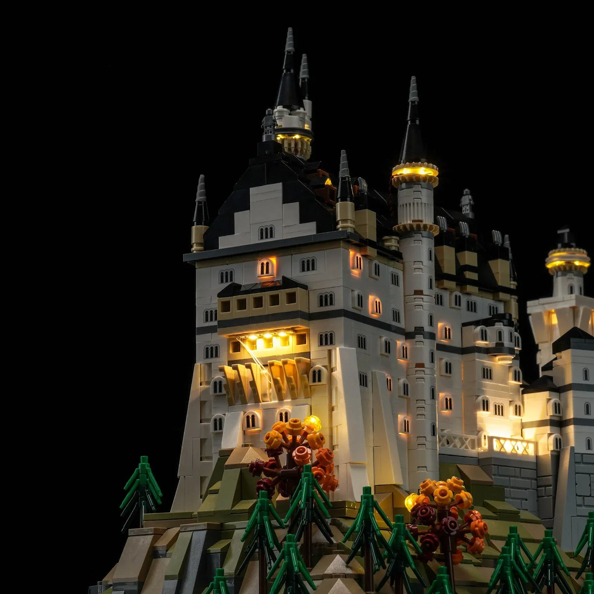 Beleuchtetes Lego Schloss Neuschwanstein Modell auf einem Hügel mit Bäumen