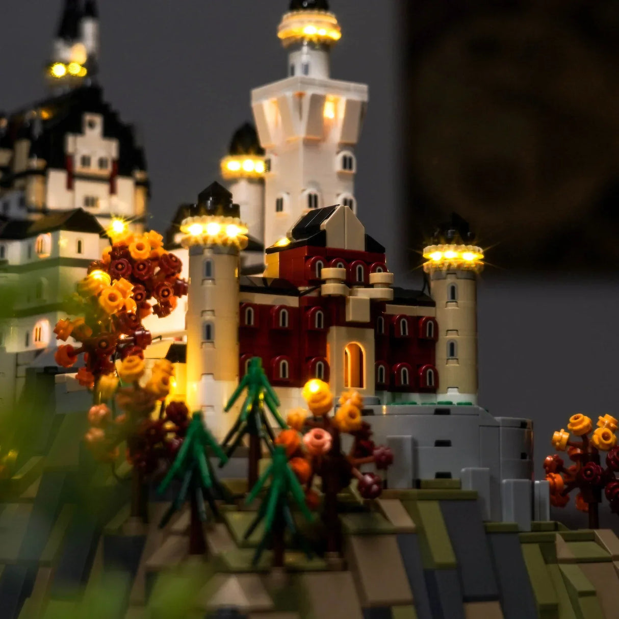 Beleuchtetes Lego-Schloss Neuschwanstein mit Bäumen und Türmen bei Nacht
