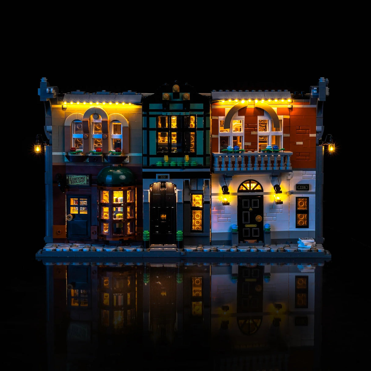 Beleuchtetes Lego-Gebäude mit drei Geschäften und Wohnungen bei Nacht
