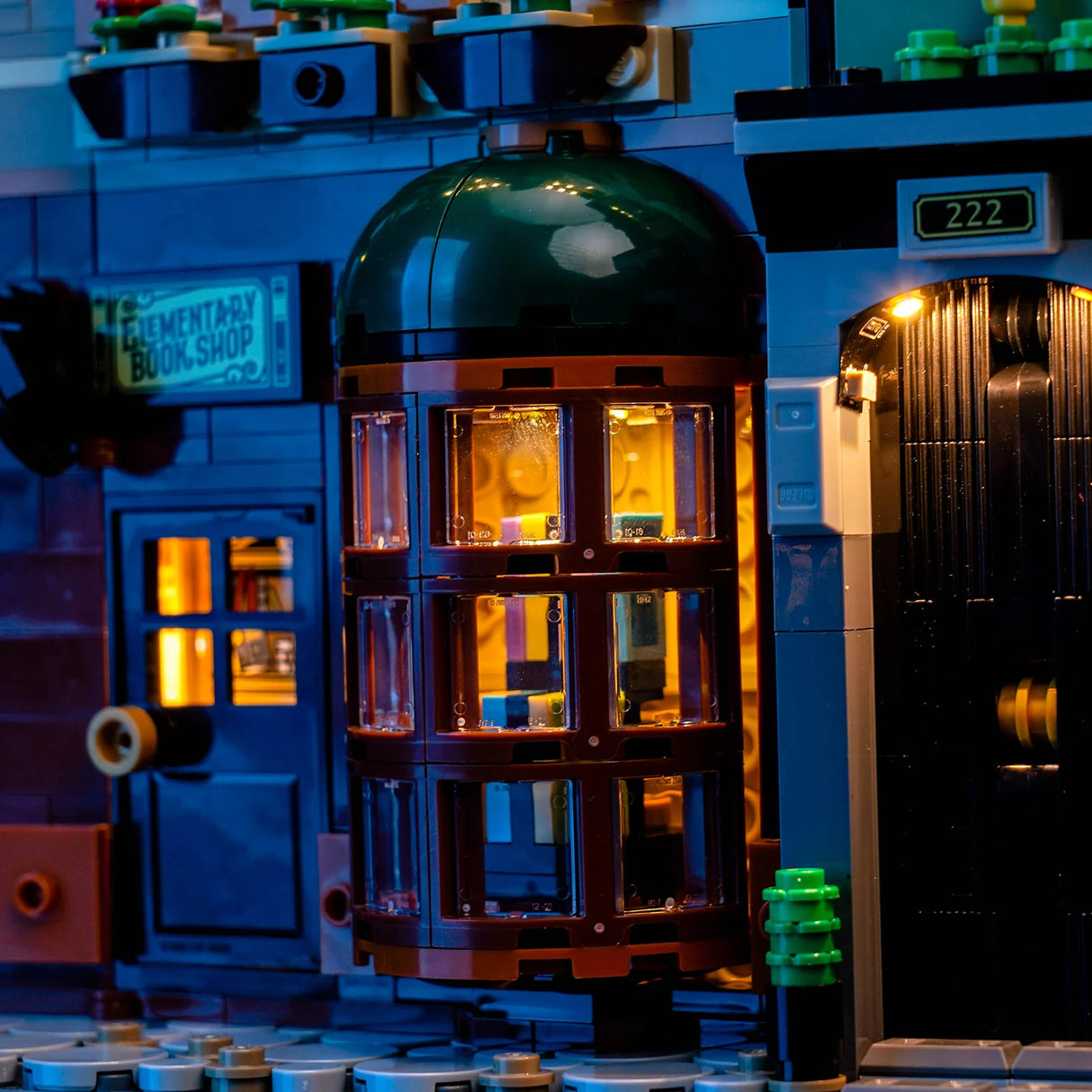 Nahaufnahme eines beleuchteten Lego-Gebäudes mit einer runden Fensterfront und einem Schild Elementary Book Shop