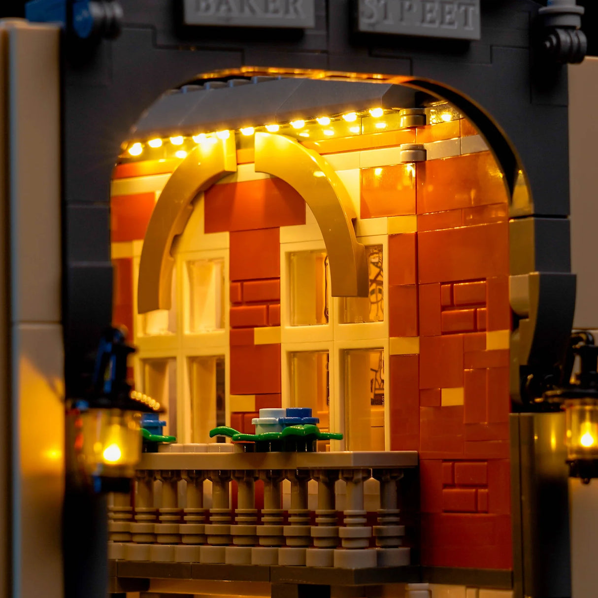 Beleuchtetes LEGO-Modell eines Gebäudes mit Bogenfenstern und Balkon, Laternen an den Seiten