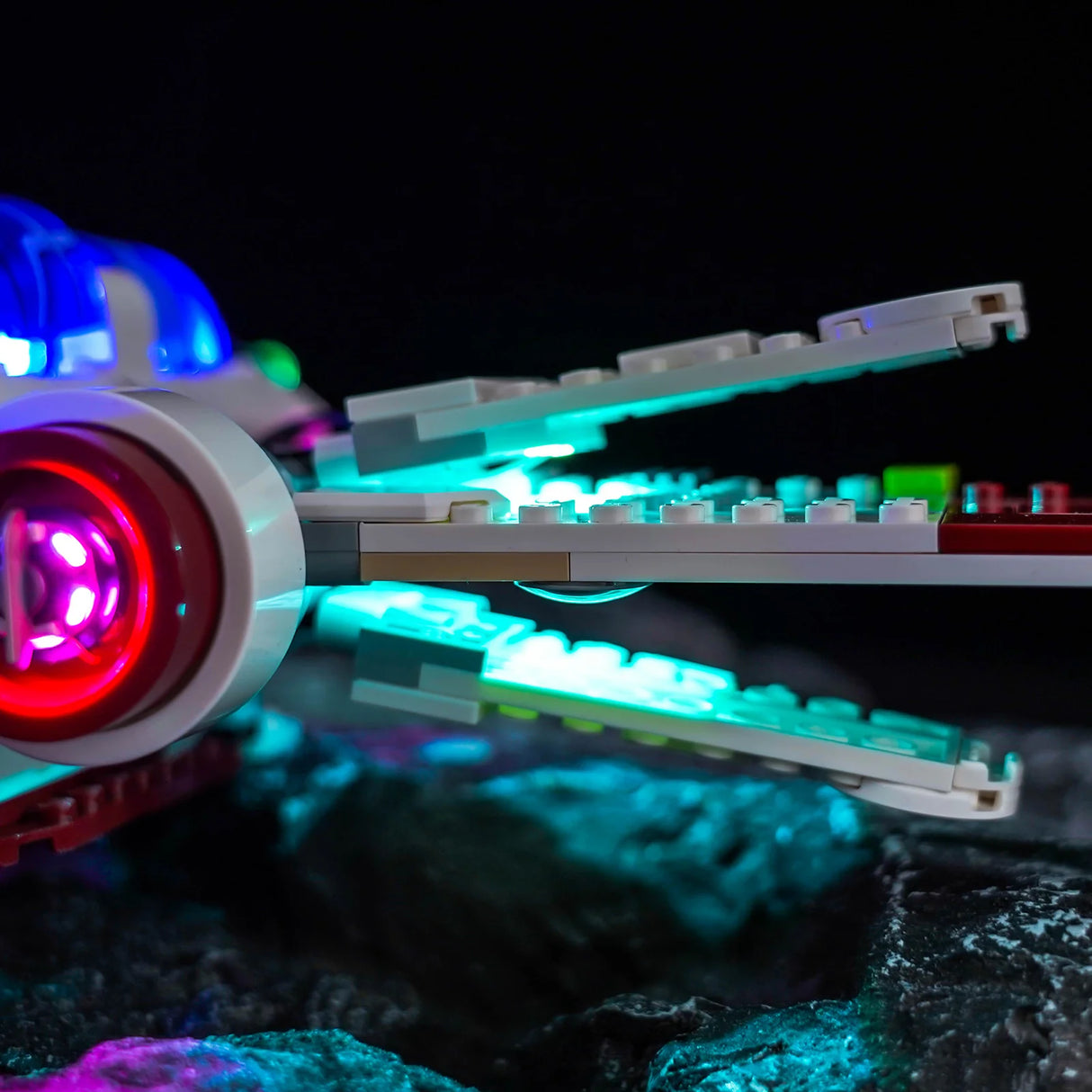 Nahaufnahme eines beleuchteten Lego-Raumschiffs mit roten, blauen und türkisen Lichtern auf dunklem Hintergrund