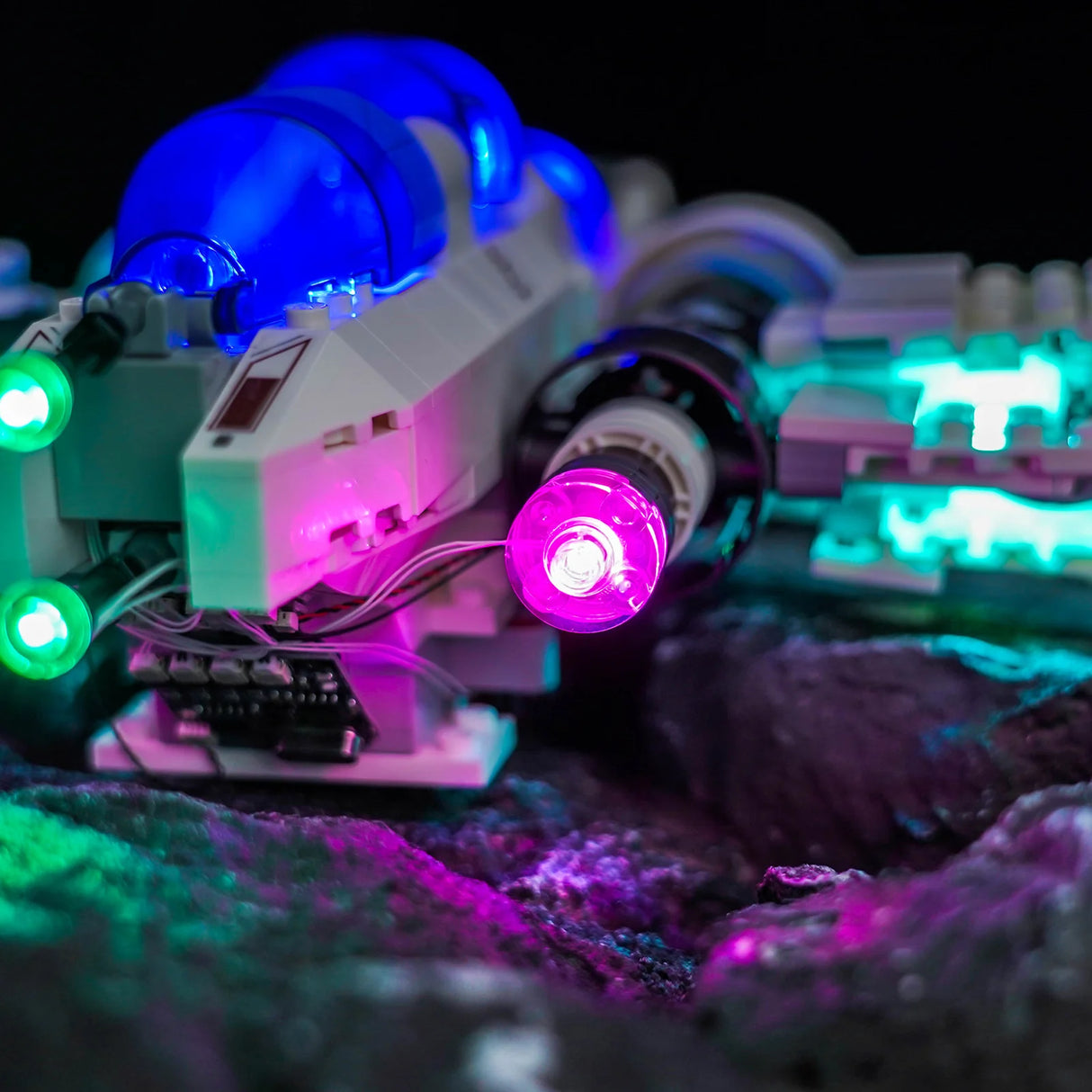 Nahaufnahme eines beleuchteten LEGO Raumschiffs mit blauen, grünen und violetten Lichtern