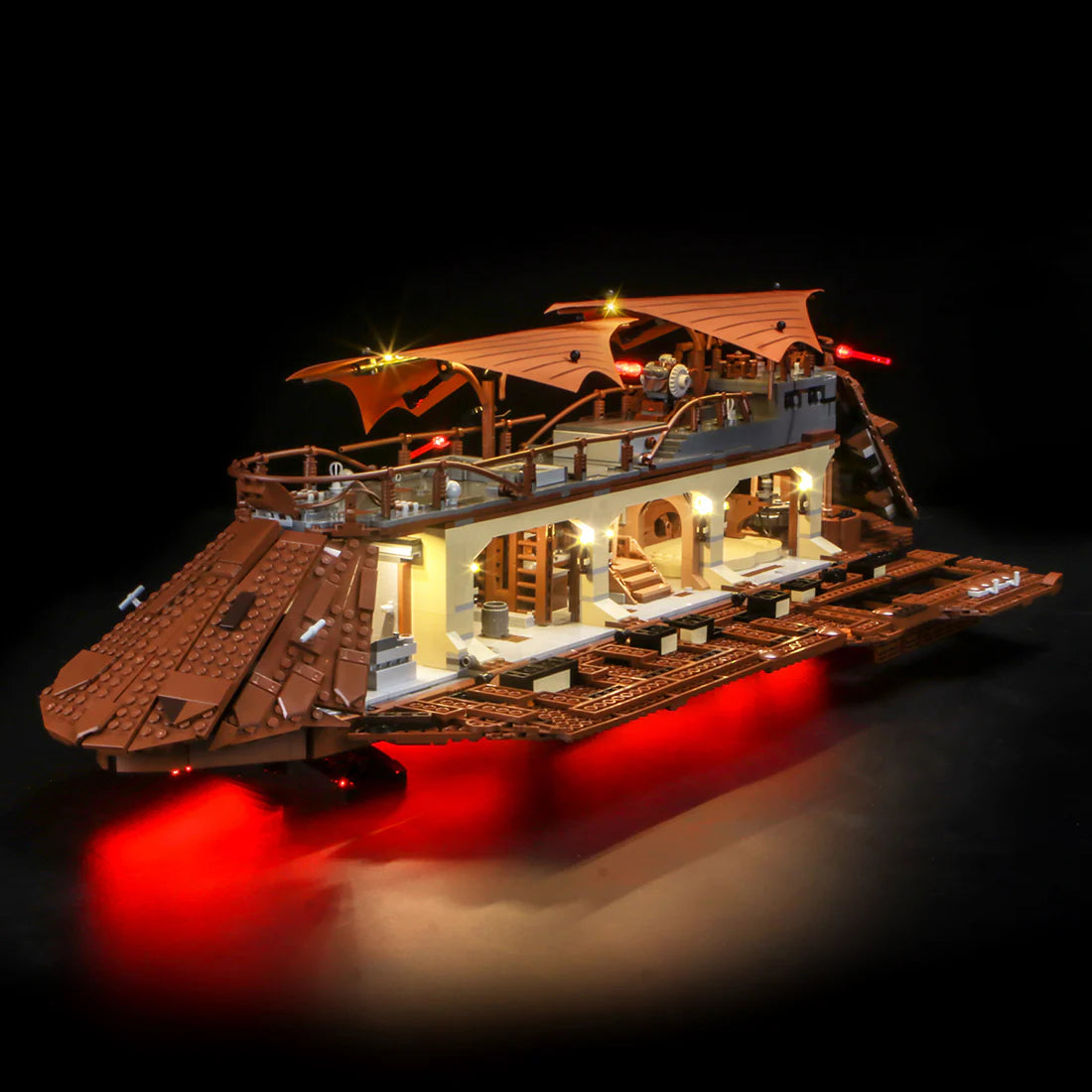 Beleuchtetes Lego Modell eines Segelschiffs aus braunen Bausteinen vor schwarzem Hintergrund